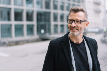 Mature smiling man with glasses wearing black coat