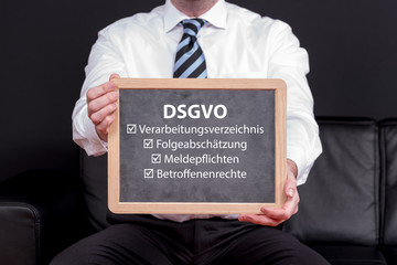 Geschäftsmann mit einer Tafel zur DSGVO mit Schlagworten