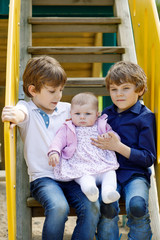 Fototapeta na wymiar Two little happy kid boys with newborn baby girl, cute sister.