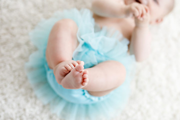 Close-up of legs and feet of baby girl on white background wearing turquoise tutu skirt. © Irina Schmidt