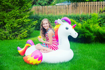 Beautiful teen age model girl in summer day ready to play with air unicorn at green back yard © Deksbakh
