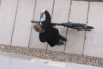 Man wheeling a bicycle along a sidewalk