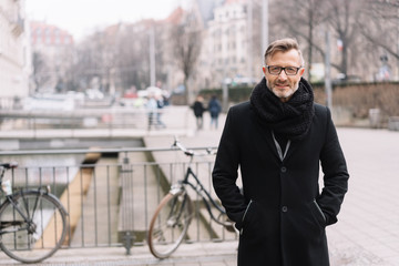 Street portrait of cheerful man in black coat