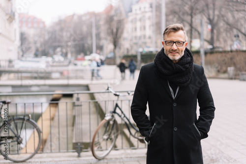 Street portrait of cheerful man in black coat