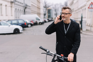 Mature man with bicycle talking on mobile phone