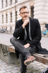 Thoughtful man sitting on a bench in town