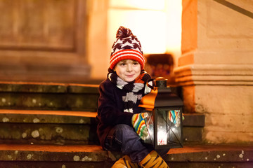 Little cute kid boy with with a light lantern on stairs near church. © Irina Schmidt