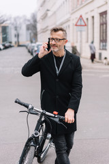 Man standing chatting on a mobile holding a bike