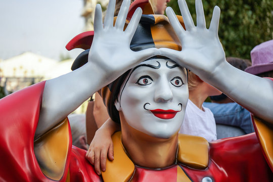 Colorful figure of a clown with arms raised.