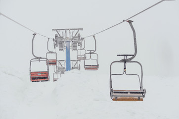 Chairs of a ski lift heading into the fog