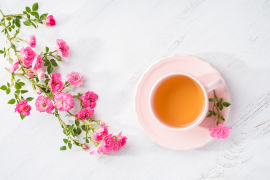 Cup Of Tea And Branch Of Small Pink  Roses On Rustic Table. Flat Lay