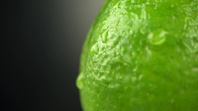 Lime crust with Water Drops on a black background. Water drops on a citrus close up. Macro shooting of a citrus. Green juicy lime, Rotation 4K
