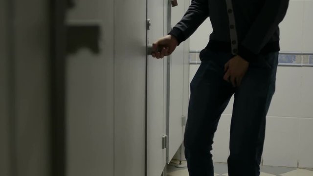 man with urinary incontinence in public restroom near closed toilet cabin