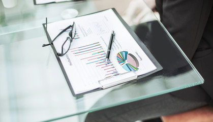 financial chart,glasses and pen on the workplace of the businessman