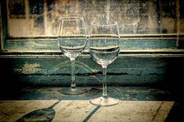 Two empty wine glasses on an antique window, wine is poured into glass. Wine tasting, restaurant, St. Valentine's Day, winemaking