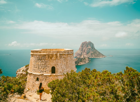  Islotes de Es Vedra y Es Vedranell. Mujer joven en el alto de la monta&ntilde;a observando la belleza del paisaje, al lado de la Torre Des Savinar, en el parque natural Cala D&acute;hort de Ibiza, Espa&ntilde;a