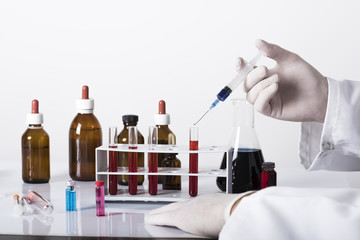 test tubes and laboratory tests with colored liquids, hand in glove holding test tube