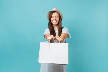 Portrait happy excited smiling beautiful caucasian woman in summer dress, straw hat holding packages bags with purchases after shopping isolated on blue pastel background. Copy space for advertisement