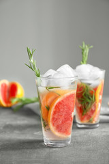 Fresh grapefruit cocktail with rosemary in glass on grey table