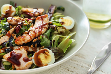 Plate with tasty chicken salad on wooden table