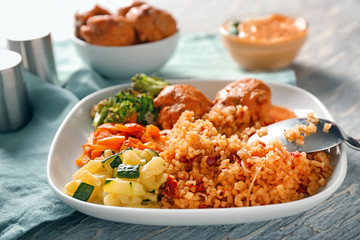 Tasty boiled rice with meatballs and vegetables on plate