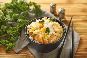 Bowl with boiled rice, meat and vegetables on wooden table