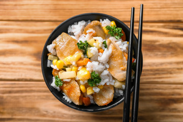 Bowl with boiled rice, meat and vegetables on wooden table
