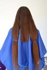 Стрижка на  длинных волосах, парикмахер обрезает прядь волос