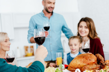 selective focus of family with wine glasses celebrating thanksgiving at served table