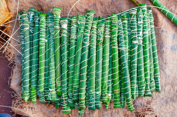 traditional cameroonian bâton de manioc made of manioca wrapped in plantain leaves on ground in...