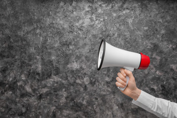 Woman holding megaphone on grey background