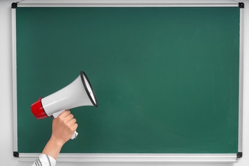 Hand of woman with megaphone against chalkboard