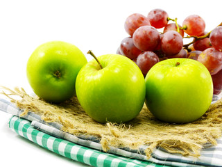 green apple and red grapes on tablecloth