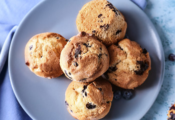 Plate with tasty blueberry muffins on table