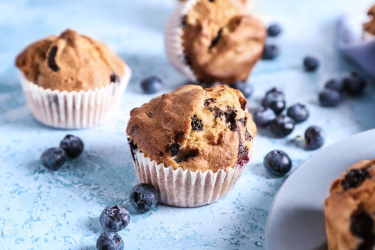 Tasty blueberry muffins on color background