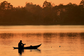 Silhouette of a fisherman working on the lake during the sunset 