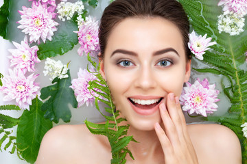 Portrait of young sexy beauty female woman smiling with clean pure skin taking spa relaxing in bath with flowers and green leafs white soap water. Skin beauty health care concept. Body part and nature