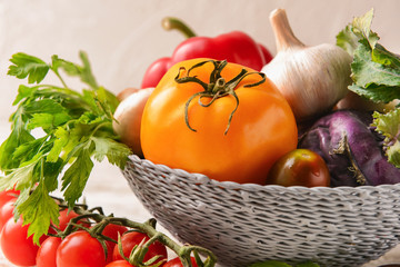 Wicker bowl with various fresh vegetables on table