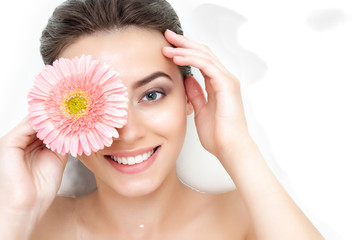 Portrait of cute beauty female woman adult with clean pure skin with pink flower taking spa...