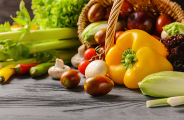 Various fresh vegetables with wicker basket on wooden table