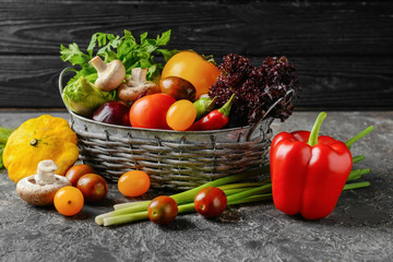 Basket with various fresh vegetables on dark table