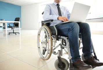 Businessman in wheelchair working with laptop in office