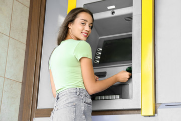 Fototapeta na wymiar Woman inserting credit card into cash machine outdoors