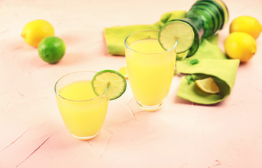 Glasses of fresh lemon juice on color background