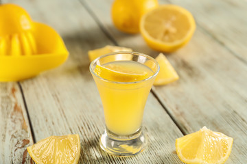 Glass of fresh lemon cocktail on light wooden table