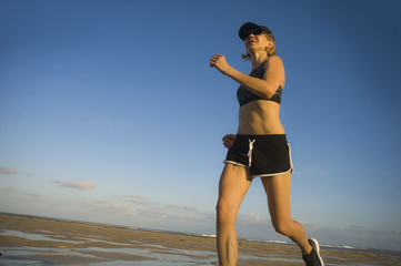 isolated background portrait of young happy and attractive fit woman running on the beach in outdoors jogging workout in fitness training and healthy sporty lifestyle