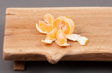 Wooden cutting board on grey background with mandarin