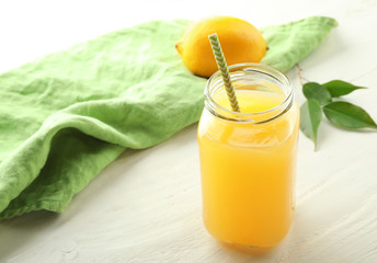 Jar of fresh lemon juice on white wooden table