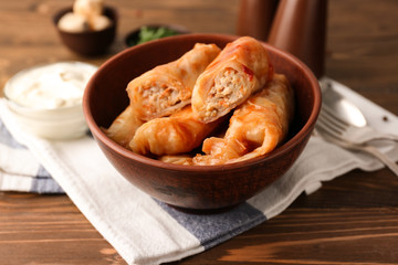 Bowl with stuffed cabbage leaves on wooden table