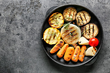 Pan with tasty grilled vegetables on grey table